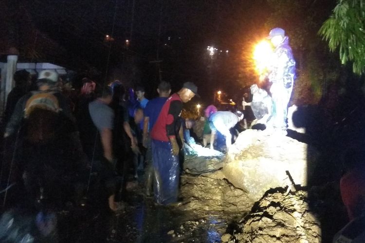 Pembersihan material longsor yang menutup badan jalan di jalur penghubung Pacet - Trawas, Kabupaten Mojokerto, Jawa Timur, dilakukan petugas dengan bantuan alat berat, Jumat (7/2/2020) malam.