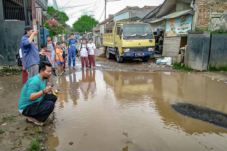 Warga melaksanakan aksi mancing bersama di jalan rusak sebagai aksi protes kepada Pemkab Bandung Barat, Senin (27/2/2023).