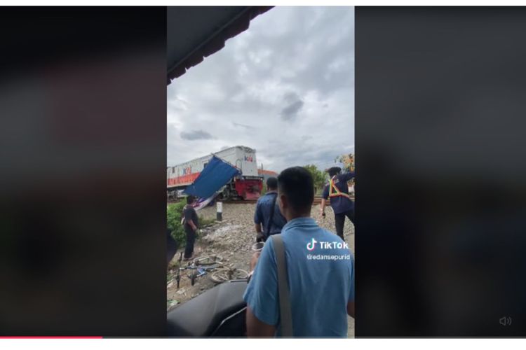 Seorang warga merekam detik-detik ketika kereta lokal Bandung Raya menyeret tena berwarna biru milik PKL paada Minggu (5/2/2023).