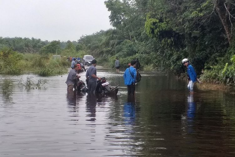 Sebuah sampan pengangkut dua unit sepeda motor terbalik saat melewati genangan banjir di Desa Kualu, Kecamatan Tambang, Kabupaten Kampar, Kamis (19/12/2019).