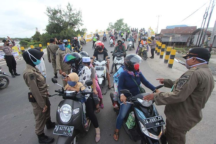 Petugas memeriksa identitas diri warga saat hari pertama Pembatasan Sosial Berskala Besar (PSBB) di perbatasan Kota Banjarmasin, Kalimantan Selatan, Jumat (24/4/2020). Pemerintah Kota Banjarmasin resmi menerapkan PSBB dalam rangka percepatan penangan COVID-19 selama 14 hari dimulai 24 April hingga 7 Mei 2020.