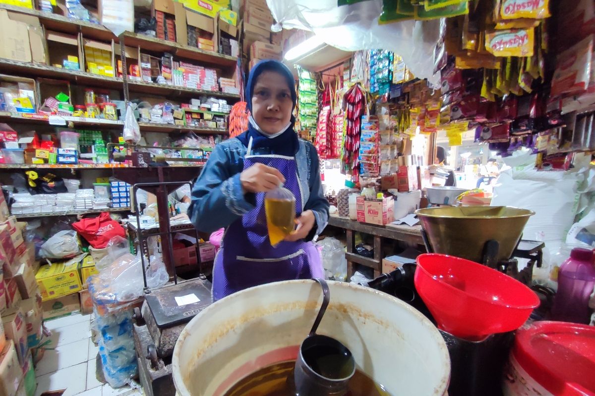 Yuli salah satu pelayan di Toko Sembako Handoko Pasar Pagi Kota Cirebon, Jawa Barat, menunjukan minyak goreng curah yang baru saja dia bungkus, Senin (27/6/2022).