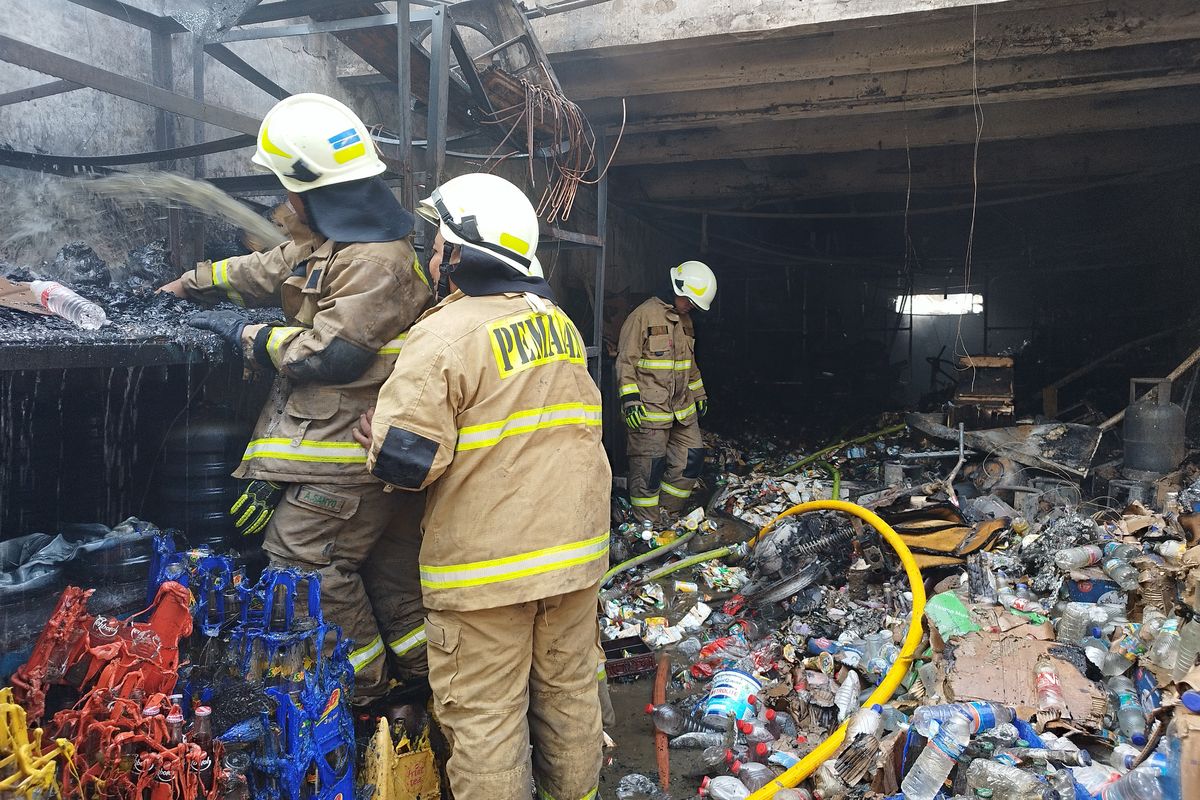 Petugas pemadam kebakaran menyiram sisa kerat minuman botol kaca di agen sembako yang terbakar, Jalan Angkasa Dalam 2 No 54 A, RT 011/RW 03, Gunung Sahari Selatan, Kemayoran, Jakarta Pusat, Senin (2/10/23) pagi. (KOMPAS.com/XENA OLIVIA)