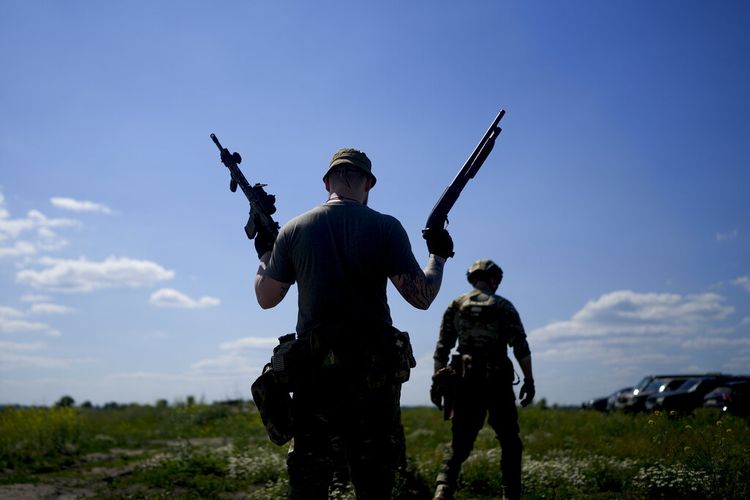 Seorang anggota milisi sipil memegang senapan dan senapan selama pelatihan di lapangan tembak di pinggiran Kyiv, Ukraina, Selasa, 7 Juni 2022. (AP Photo/Natacha Pisarenko)