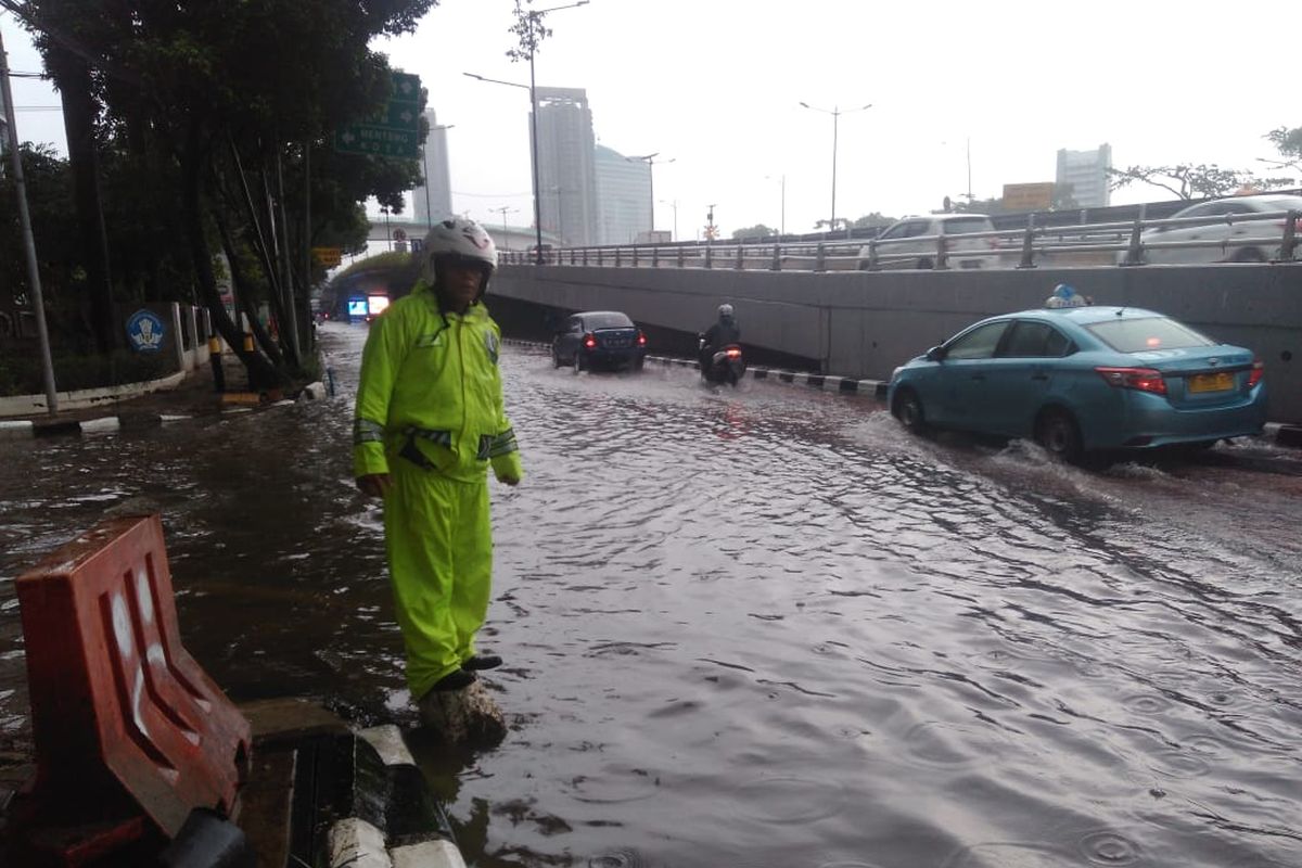 Petugas kepolisian mengatur lalu lintas saat genangan air terlihat di Jalan Gatot Subroto, Jakarta Pusat, Sabtu (18/1/2020).