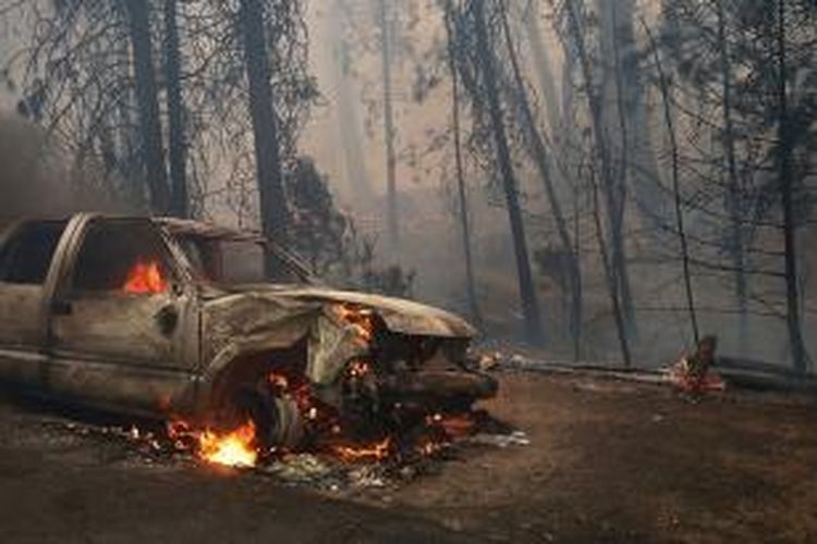 Sebuah mobil terbakar di dekat taman nasional Yosemite, California, AS, Minggu (25/8/2013). Kebakaran ini membuat pihak taman nasional harus mengevakuasi para pengunjung taman nasional itu.