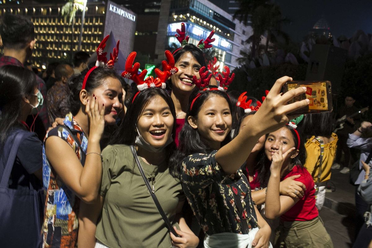 Warga mengambil swafoto saat menonton Christmas Carol di depan Grand Hyatt, Gondangdia, Menteng, Jakarta Pusat, Kamis, (19/12/2019). Tak hanya di bundaran HI, event ini juga digelar sejumlah spot ruang publik di sepanjang MH Thamrin - Sudirman.