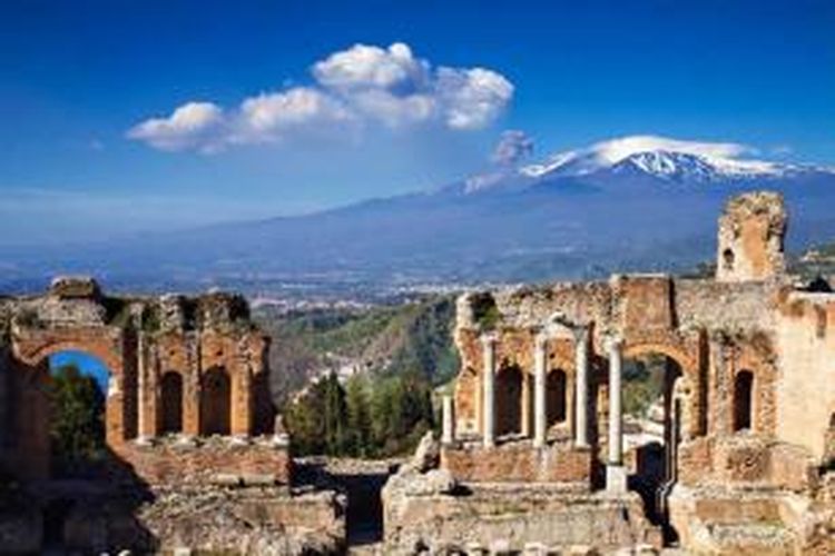 Reruntuhan bangunan Roman Theater Yunani dengan latar belakang Gunung Etna yang tengah meletus di Taormina, Sisilia, Italia. Gunung Etna salah satu gunung api teraktif di dunia, pada 21 Juni 2013, dinobatkan sebagai situs Warisan Dunia oleh UNESCO.