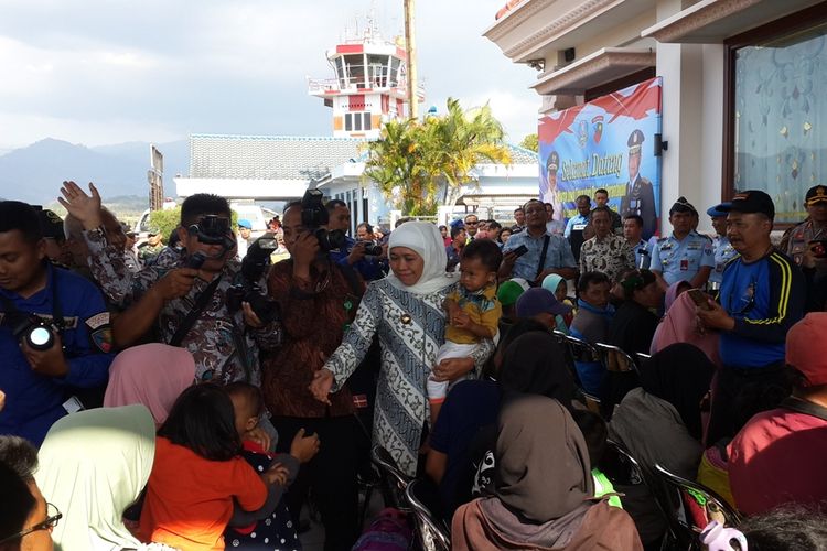 Gubernur Jawa Timur Khofifah Indar Parawansa saat menggendong anak kecil sambil menyalami warganya yang baru tiba dari Wamena, Papua di Lanud Abdulrachman Saleh, Kabupaten Malang, Rabu (2/10/2019)