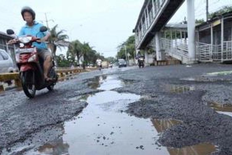 Pengendara melintas di ruas Jalan Daan Mogot, Jakarta Barat yang rusak parah, Minggu (20/1/2013). Selain aspal mengelupas dan berlubang, di ruas jalan itu juga banyak ditemui separator jalur busway yang rusak sehingga membahayakan pengguna jalan.
