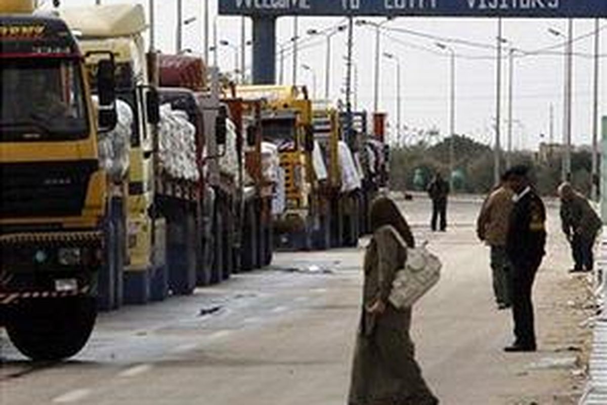 Seorang perempuan melintas di dekat antrian truk pengangkut bantuan kemanusiaan di Pintu Gerbang Rafah yang terletak antara perbatasan Mesir dan Kota Gaza, 18 Januari 2009 