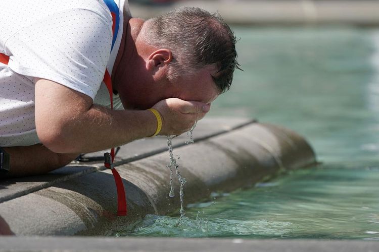 Seorang laki-laki tampak menyegarkan wajah di air mancur di Trafalgar Square, London pusat, Selasa (19/07/2022). Inggris tengah dilanda gelombang panas dengan suhu yang mencetak rekor hingga di atas 40 derajat Celcius pada wilayah tertentu.