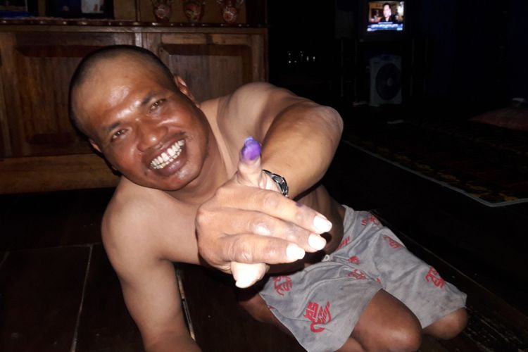 Syamsul Bahri (43), penyandang difabel memperlihatkan jarinya usai mencoblos. Rabu, (27/6/2018).