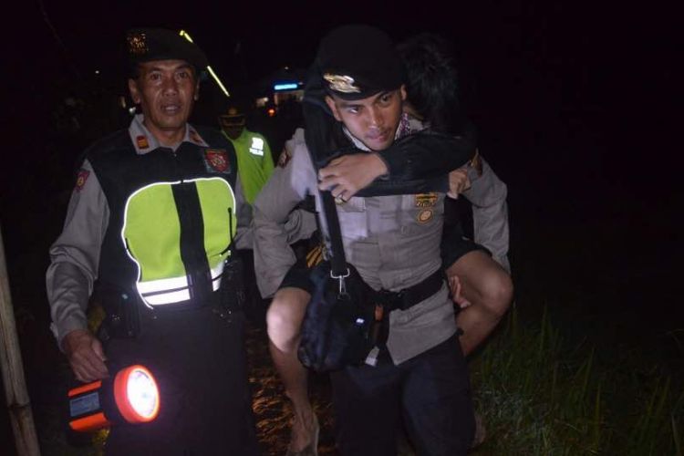 Petugas polisi resort Wonosobo mengggendeng salah seorang pendaki yang mengalami luka-luka akibat tersambar petir saat melakukan pendakian di kawasan Gunung Prau, Minggu (23/4/2107) malam. 