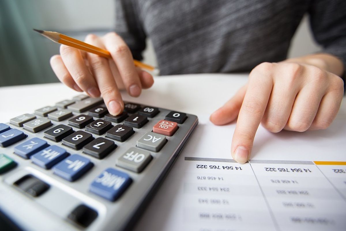 Closeup of accountant counting on calculator and working with table