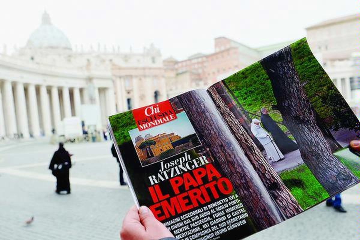  Wisatawan membaca majalah Italia, Chi di Lapangan Santo Petrus, Vatikan, Rabu (6/5). Majalah Chi menurunkan artikel tentang Paus Emeritus Benediktus XVI  dilengkapi foto  paparazi yang memotret Paus Emeritus tengah  berjalan-jalan di taman rumah peristirahatan kepausan di Castel Gandolfo, luar kota Roma.