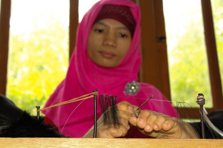 Kuswati, buruh plasma penyandang tuna daksa saat sedang menyulam bulu mata palsu di rumahnya di Desa Panusupan, Kecamatan Rembang, Purbalingga, Jawa Tengah, Minggu (29/4/2018).
