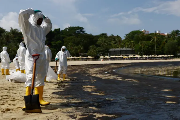 Para Pekerja yang menggunakan baju pelindung membersihkan tumpahan minyak di obyek wisata Pantai Tanjong, Minggu.