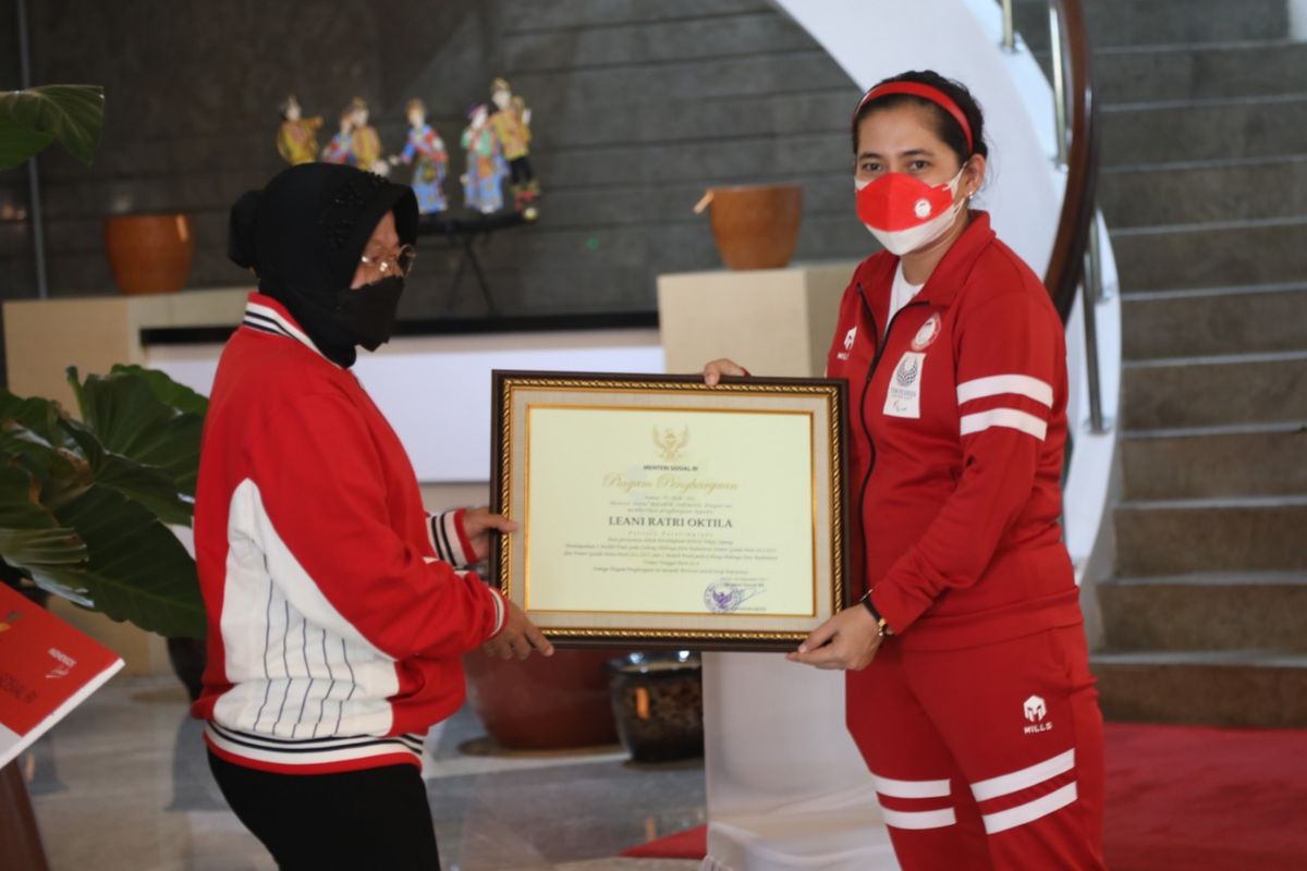 Menteri Sosial (Mensos) Tri Rismaharini memberikan piagam penghargaan kepada Leani Ratri Oktila, atlet penyandang disabilitas yang mendapatkan 2 medali emas dan 1 medali perak pada cabang olahraga para badminton Paralimpiade Tokyo 2020, Jumat (24/9/2021).
