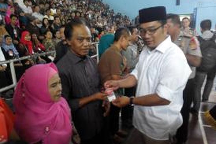 Wali Kota Bandung, Ridwan Kamil, membagikan kartu tanda pengenal khusus kepada sekira 1000 Pedagang Kaki Lima  (PKL) di Gor Koni Kota Bandung, Jumat (9/5/2014). Kartu khusus PKL tersebut dibagikan hanya untuk pedagang yang memiliki KTP Bandung.