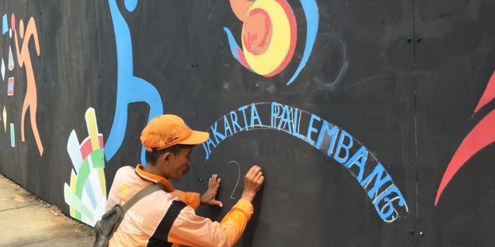 Petugas penanganan prasarana dan sarana umum (PPSU) atau pasukan oranye Kelurahan Pondok Pinang menggambar mural Asian Games 2018 di perempatan Pondok Indah Mall, Jakarta Selatan, Rabu (25/7/2018).