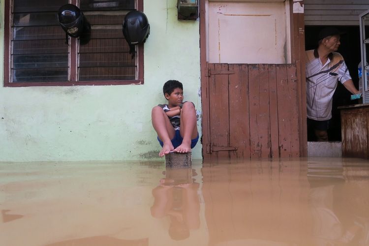 Warga berada di depan rumahnya yang terendam banjir di Jalan Kelinci, Pasar Baru, Jakarta Pusat, Kamis (2/1/2020). Banjir terjadi akibat tingginya curah hujan serta buruknya sistem drainase di kawasan tersebut. ANTARA FOTO/M Risyal Hidayat/wsj.