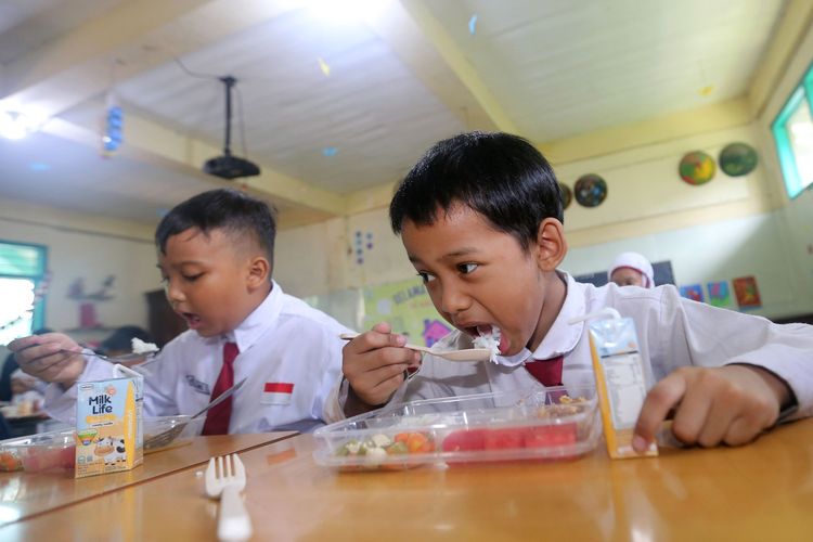 Dua siswa SD di Surabaya tampak lahap menikmati menu empat sehat lima sempurna yang disediakan melalui Program Makan Bergizi Gratis (MBG). Program ini bertujuan meningkatkan asupan gizi siswa untuk mendukung aktivitas belajar di sekolah.