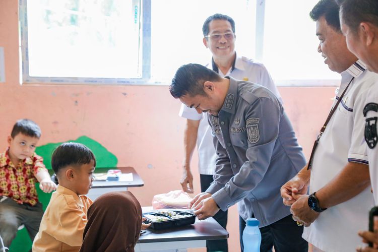 Pj Walikota Pekanbaru Risnandar Mahiwa terlihat menyerahkan paket makan siang secara langsung kepada siswa SDN 185 Pekanbaru dalam simulasi kedua program makan siang bergizi, Rabu (2/10/2024). 