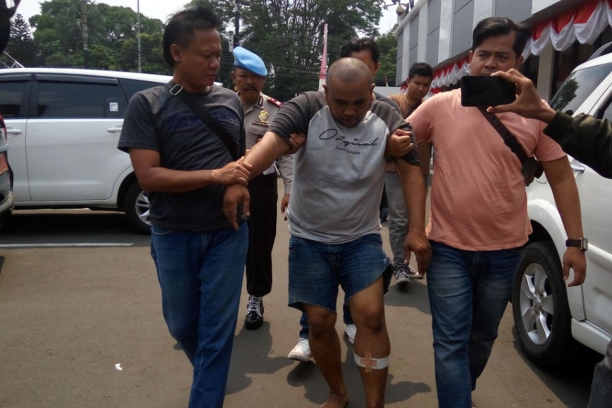 Baihazi Sakom alias Boy (34), pemerkosa terhadap seorang perempuan di Depok pada pekan lalu, tampak berjalan dengan kaki pincang saat dibawa ke Mapolresta Depok pada Rabu (30/8/2017). Boy disebut sempat berupaya kabur saat disergap polisi di tempat persembunyiannya di Cilebut, Kabupaten Bogor pada Rabu dinihari. Polisi akhirnya melepaskan tembakan yang mengenai kaki kiri Boy.  