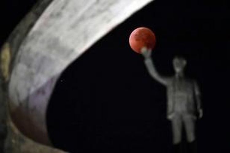 Gerhana bulan terlihat dengan latar depan patung di Juscelino Kubitschek Memorial di Brasilia, 15 April 2014. Gerhana bulan kali ini terbilang langka karena bulan berubah warna dari oranye ke merah darah.