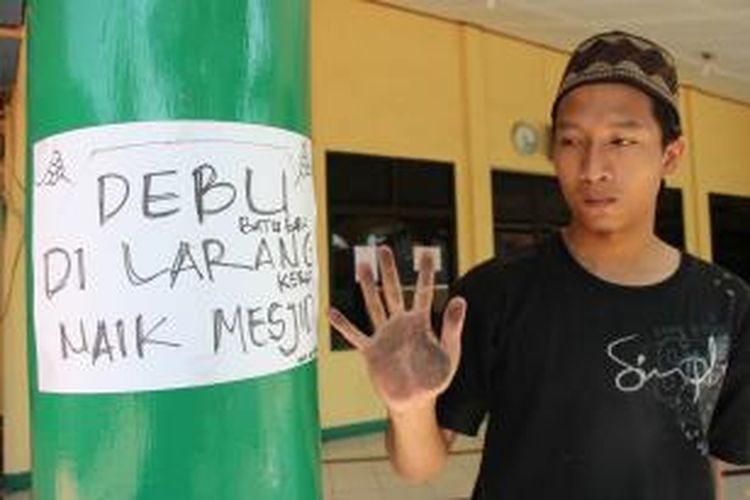 Daim (24), warga Gang Nelayan, Kelurahan Panjunan, Kecamatan Lemahwungkuk, Kota CIrebon, Jawa Barat, menunjukan telapak tangan yang dipenuhi debu batu bara di areal Masjid Alikhas, Selasa (22/92015). Ia menempelkan kertas 