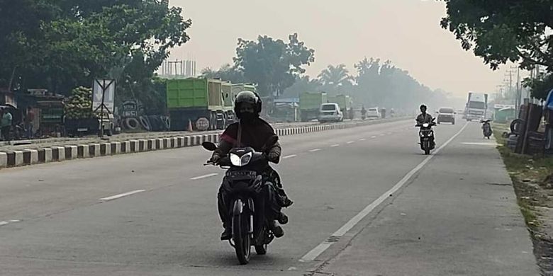 Pengendara sepeda motor menerobos kabut asap karhutla di jalan lintas Pekanbaru-Bangkinang, Kabupaten Kampar, Riau, Rabu (4/10/2023) pagi.