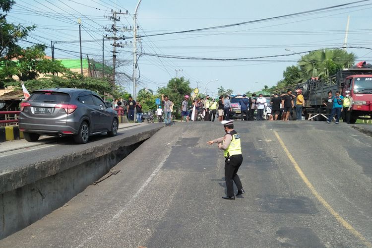 Polisi menunjukkan kondisi Jembatan Ngaglik 1 di Jalan Jaksa Agung Suprapto, Lamongan, Jawa Timur, yang patah dan kemudian ambles, Selasa (29/3/2022).