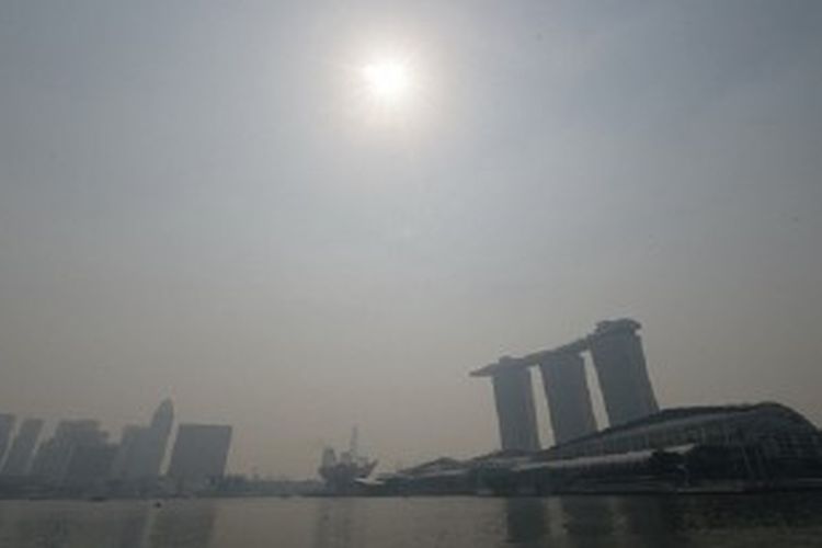 Kabut asap menghalangi sinar matahari di atas hotel-hotel di Marina Bay Sands dan pusat bisnis di Singapura, Rabu (19/6).