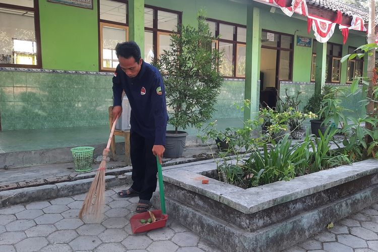 Sugiri, seorang penjaga sekolah yang sedang membersihkan halaman sekolah di SDN 2 Banjarejo, Kabupaten Blora, Jawa Tengah, Rabu (2/8/2023)