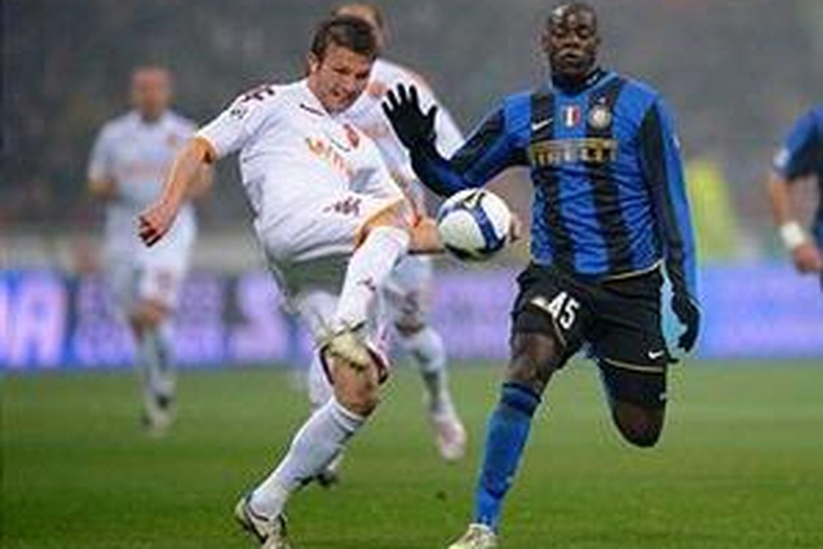 Striker Inter Milan Mario Balotelli (kanan) saat berduel dengan pemain AS Roma, Marco Motta, dalam laga di Giusepee Meazza, Minggu (1/3).