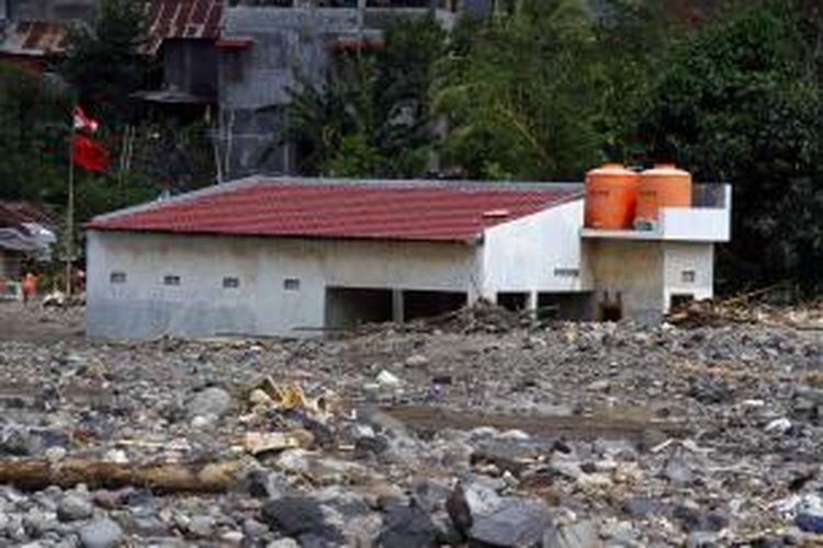 Sebuah rumah yang terletak di tepi sungai rusak akibat tertimbun batu yang dibawa banjir bandang di Manado.