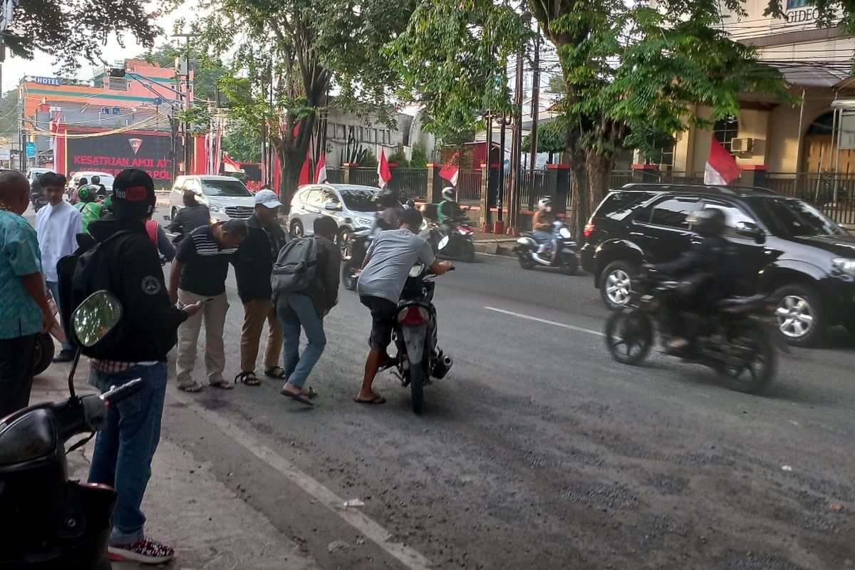Saat warga tengah menolong pengendara motor yang terjatuh akibat kondisi jalan yang rusak di Jalan Komjen Pol Jasin, Tugu, Cimanggis, Depok, pada Jumat (3/3/2023).