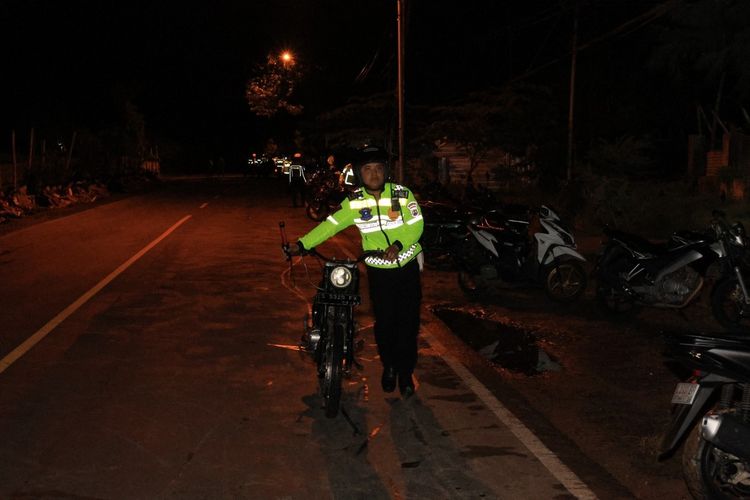 Petugas kepolisian mendorong sepeda motor yang ditinggal lari joki nya di lokasi aksi balap liar di Jalan Raya Deandles Tuban - Palang, Kecamatan Palang, Kabupaten Tuban, Jawa Timur.