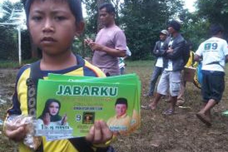 Seorang anak kecil yang hadir di acara kegiatan PPP di Kecamatan Puspahiang, Kabupaten Tasikmalay, memegang stiker bergambar caleg, Minggu kemarin. 