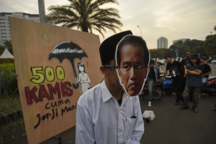 Seorang aktivis mengenakan topeng Presiden Jokowi saat aksi Kamisan ke-500 yang digelar oleh Jaringan Solidaritas Korban untuk Keadilan di seberang Istana Merdeka, Jakarta, Kamis (27/7/2017). Dalam aksi bersama itu mereka menuntut komitmen negara hadir menerapkan nilai kemanusiaan dengan komitmennya menyelesaikan kasus-kasus pelanggaran HAM berat. 