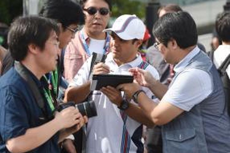 Pebalap Williams asal Brasil, Felipe Massa (tengah), dikelilingi para penggemar ketika datang di Sirkuit Suzuka untuk menjalani balapan GP Jepang, Minggu (5/10/2014).
