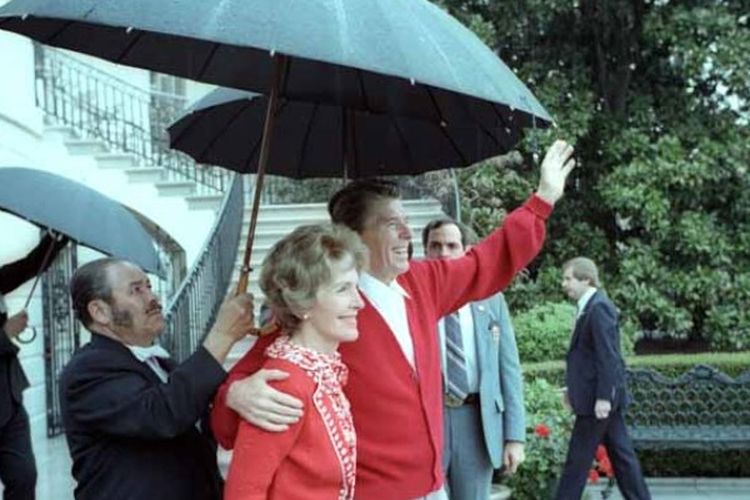 Presiden Ronald Reagan didampingi sang istri, Nancy, melambaikan tangan ke arah warga AS yang berada di luar Gedung Putih sekembalinya dari rumah sakit pada 11 April 1981.