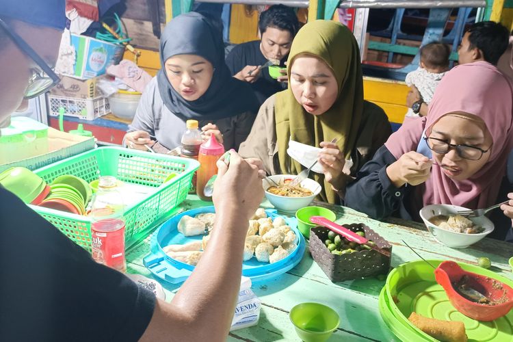 Pengunjung sedang menyantap pempek di warung terapung di pelataran Benteng Kuto Besak tepi Sungai Musi, Palembang, Minggu (20/11/2022).