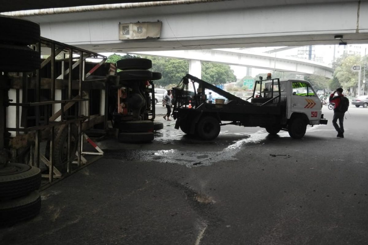 Sebuah truk trailer terguling akibat sopir berbelok menikung di Tomang, Jakarta Barat pada Kamis (28/6/2018).