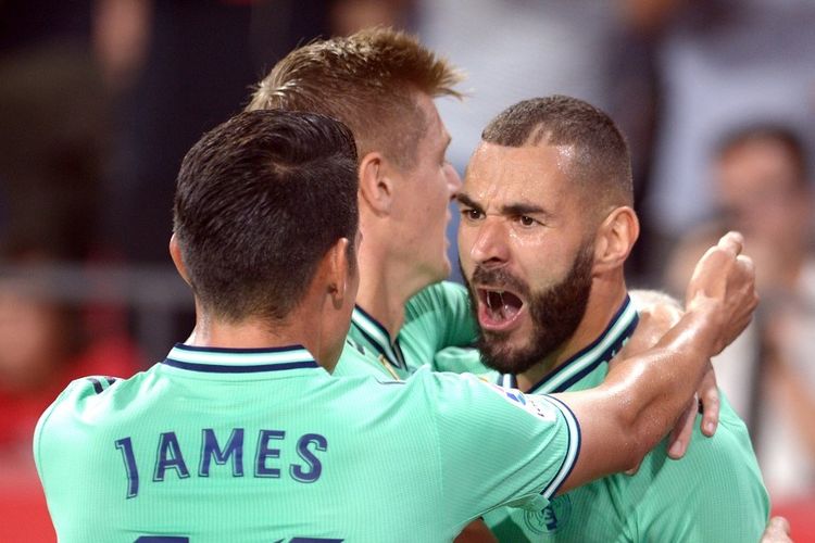 Real Madrids French forward Karim Benzema celebrates with teammates after scoring a goal during the Spanish league football match between Sevilla FC and Real Madrid CF at the Ramon Sanchez Pizjuan stadium in Seville on September 22, 2019. (Photo by CRISTINA QUICLER / AFP)