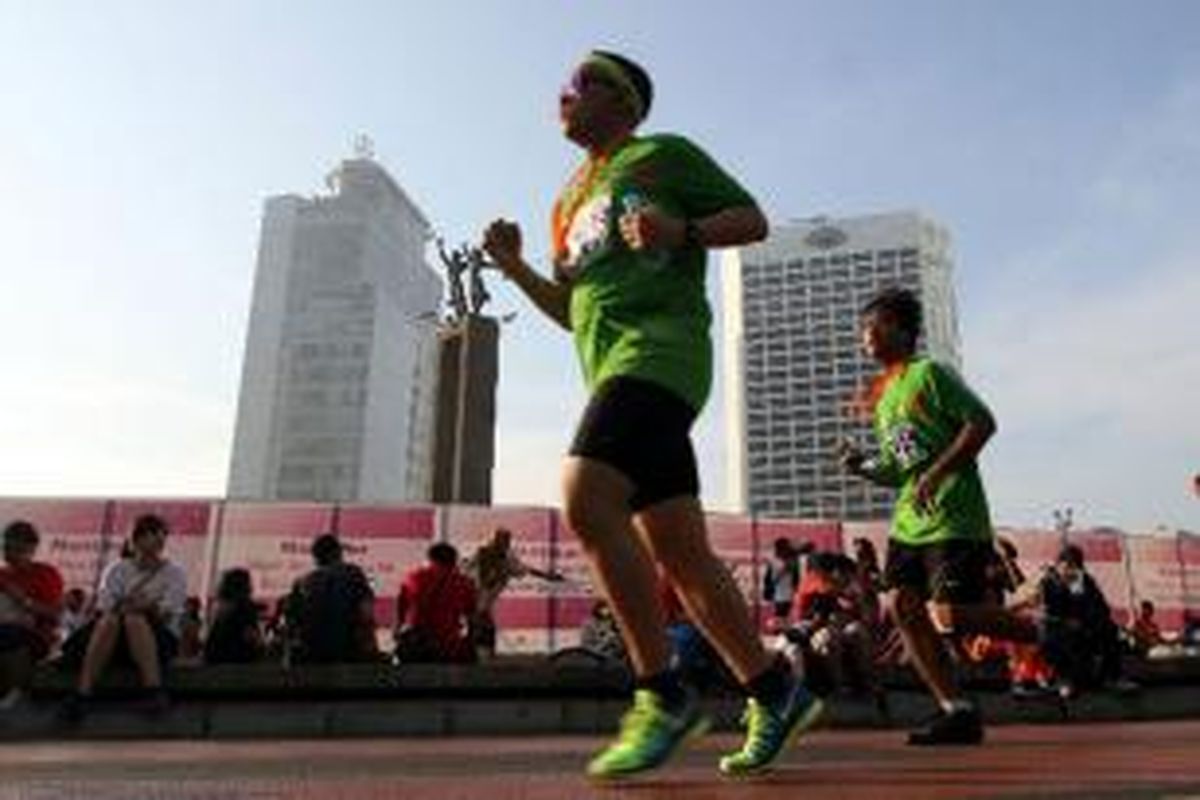 Peserta Jakarta International 10K 2014 melintas di Bundaran HI, Jakarta Pusat, Minggu (8/6/2014). Lomba lari yang diselenggarakan dalam rangka menyambut hari ulang tahun ke-487 DKI Jakarta ini diikuti oleh 35.000 peserta yang terbagi dalam empat kategori, yaitu kelompok elite internasional putra dan putri, elite nasional putra dan putri, umum, serta pelajar.