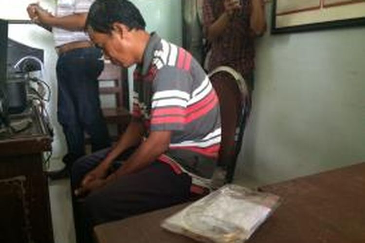 Karimullah tertunduk lesu di hadapan penyidik Polsek Kota Pamekasan setelah diamankan karena menjual emas palsu.