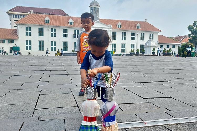 Dua orang bocah tengah bermain dengan boneka ondel-ondel di kawasan wisata Kota Tua Jakarta.