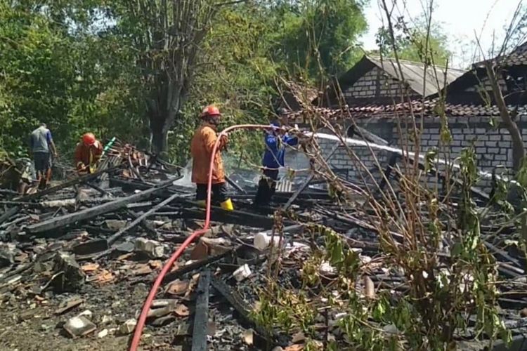 Petugas dengan dibantu warga setempat, memadamkan api yang sempat membakar rumah Ngasidah.
